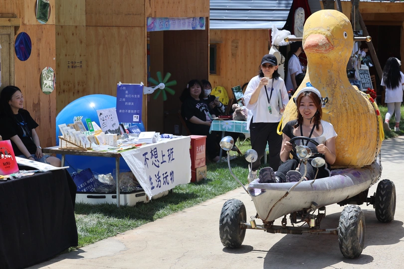 一妇女和小孩乘坐一辆由大鸭拉的小车