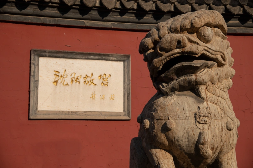 一座狮子雕像坐在红色墙前