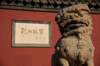 一座狮子雕像坐在红色墙前