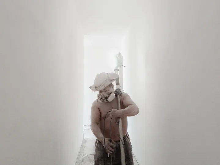 一个戴帽子的人拿着棒球棍走在白色的走廊上