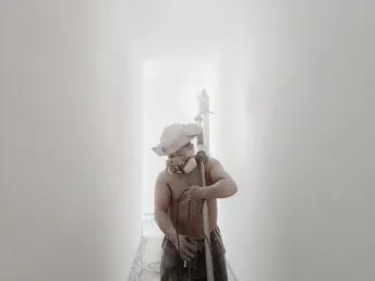 一个戴帽子的人拿着棒球棍走在白色的走廊上