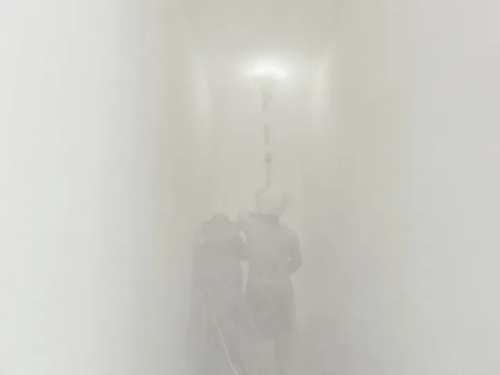 一个人骑自行车穿过雾墙 而另一个人站在摩托车旁边。