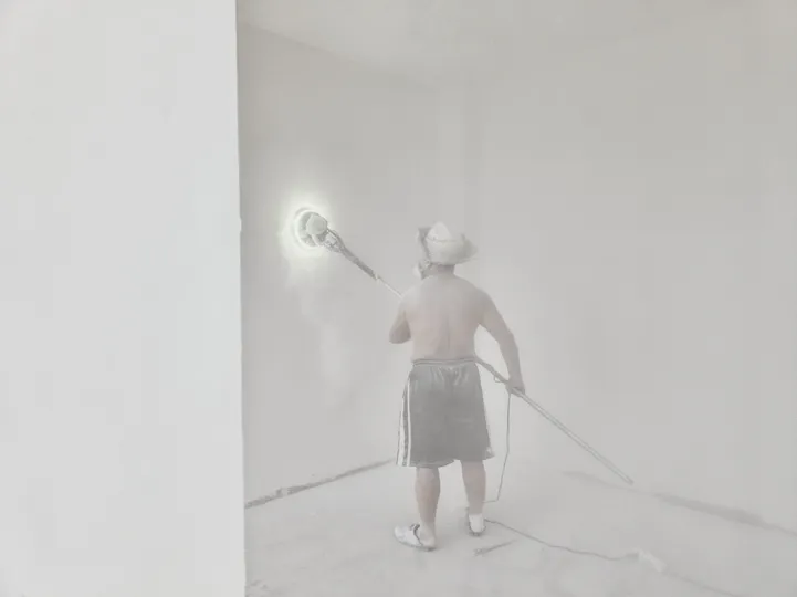 一个拿着水管的男子在白色的房间里向地板上喷水