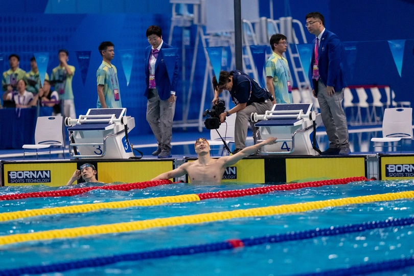 一个人在游泳池里游泳 人们站在那里观看。