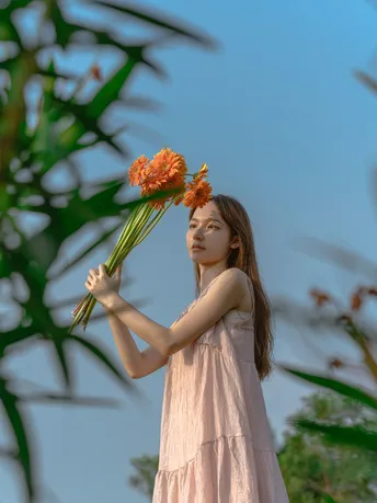 一个小女孩穿着粉红色裙子 手里拿着花。