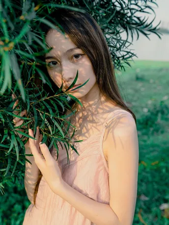 一位穿着粉红色连衣裙的年轻女子拿着一把绿色的橄榄树枝。