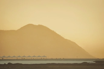 夕阳下飞越水面的飞机 海滩上有人在