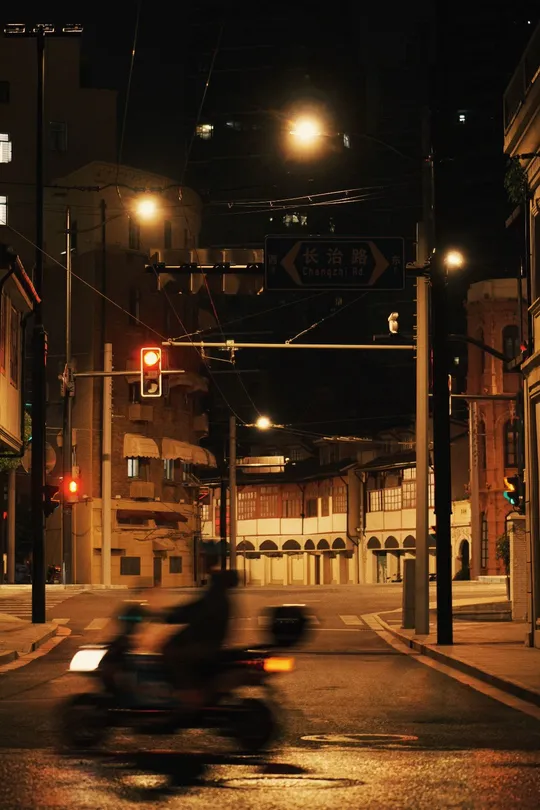 一个夜晚的黑暗城市街道 一个人在街尾骑着滑板车。