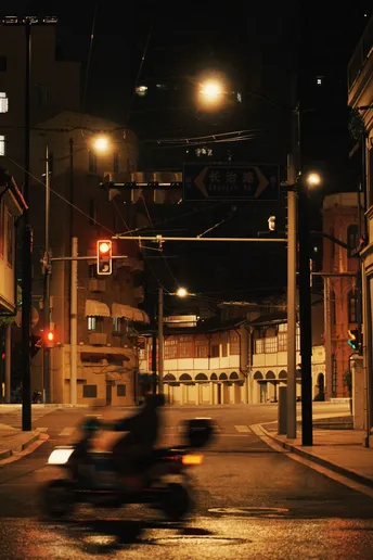 一个夜晚的黑暗城市街道 一个人在街尾骑着滑板车。