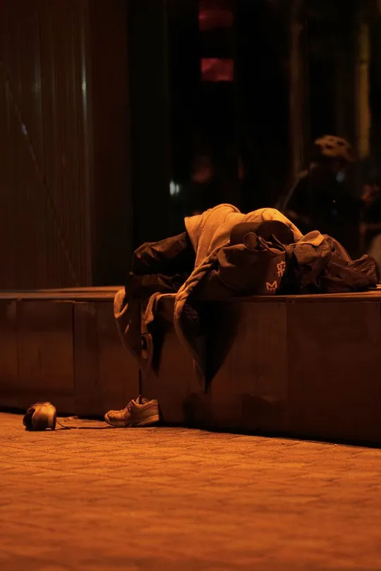 一名无家可归的人在晚上睡在人行道上的一只箱子里。