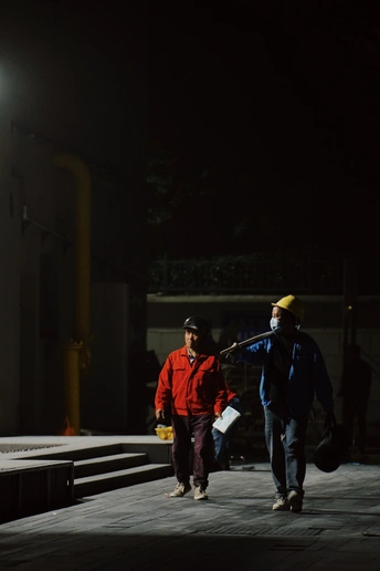 一群戴帽子和携带包的男人走在一条黑暗的街道上。