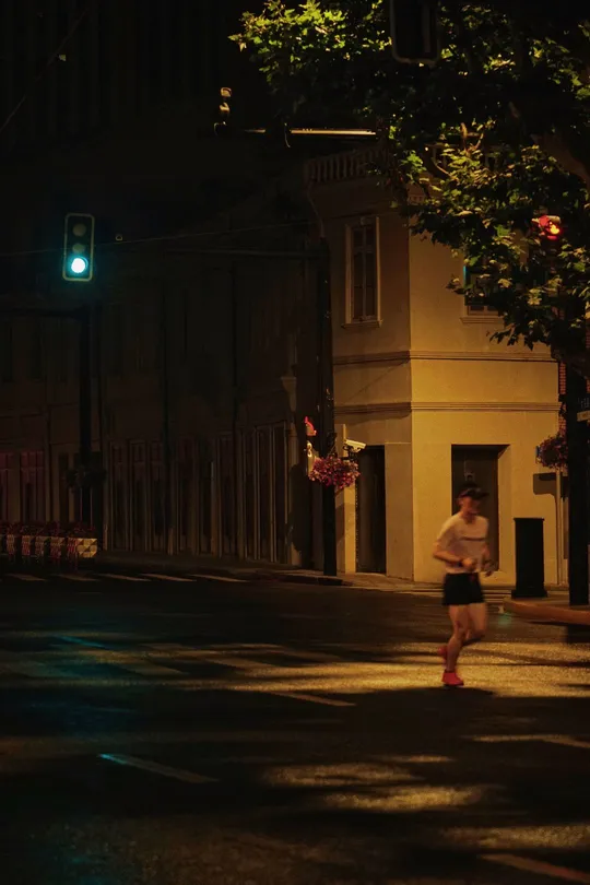 夜晚 一个男子和一个女子在黑暗的街道上跑着 带着绿光。