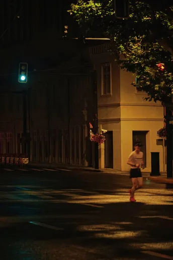 夜晚 一个男子和一个女子在黑暗的街道上跑着 带着绿光。
