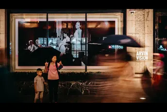 一位女士拿着雨伞 带着孩子在夜晚走人行道