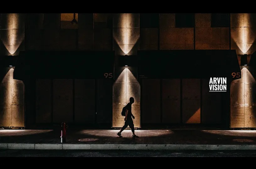 一个人和一个女人晚上走在一个有墙上的灯的路灯下