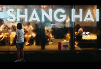 一个小女孩站在窗前看着一个年轻男孩沿着街道走下来