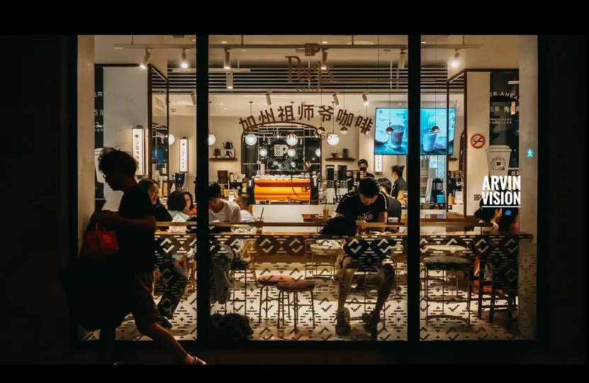 夜晚的一个咖啡店 里面有人坐着 一个男人正在走过。