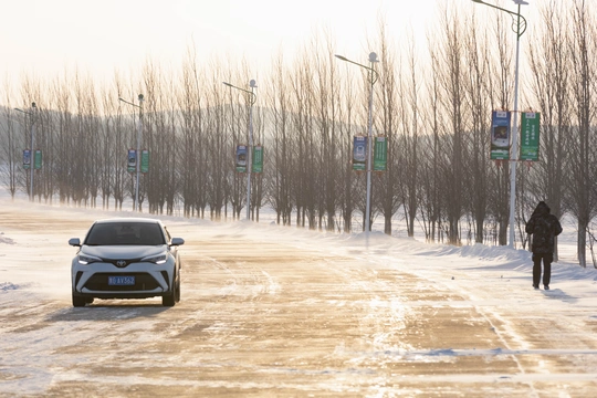 一个人走在一条铺满雪的街道上 一辆车在公路上行驶。