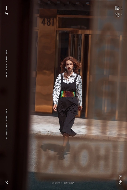 一位妇女走在街前一座建筑物的旁边