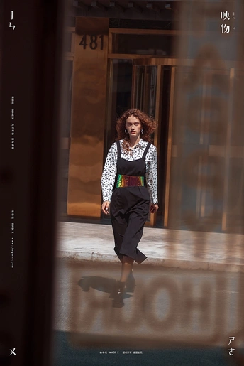 一位妇女走在街前一座建筑物的旁边