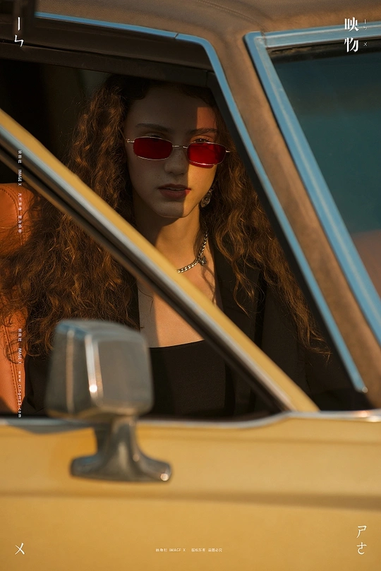 一位戴红眼镜的女性坐在黄色汽车中