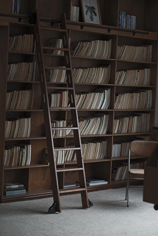 一个充满书架的书房 书架上堆满了书籍 一把带有梯子的椅子。
