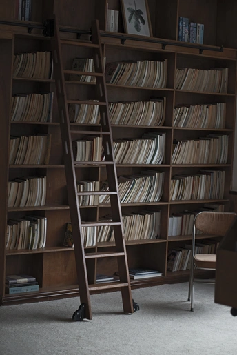 一个充满书架的书房 书架上堆满了书籍 一把带有梯子的椅子。