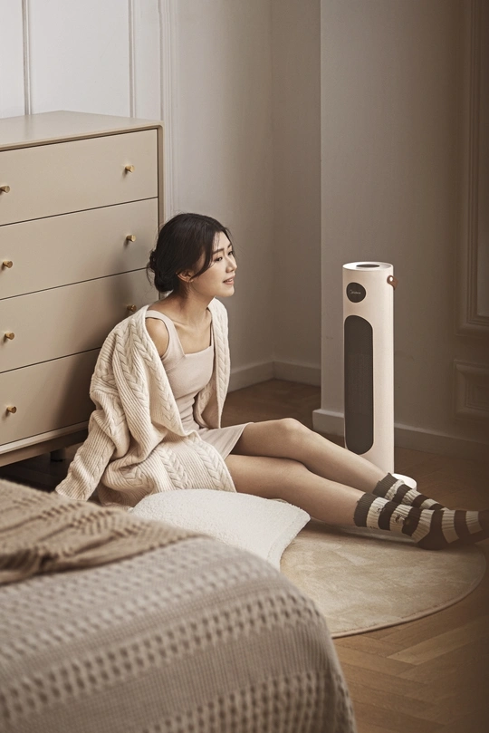 一个年轻女子坐在卧室地板上 旁边是床和扬声器。