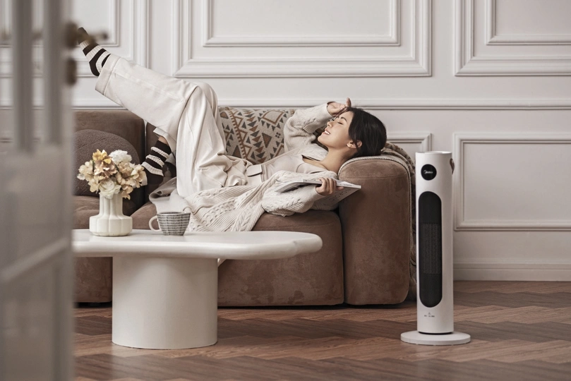 一个年轻女子躺在沙发上 旁边是一个智能设备。