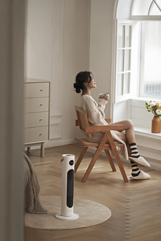 一位女士坐在椅子上 双腿交叉 手里拿着一杯咖啡或茶。