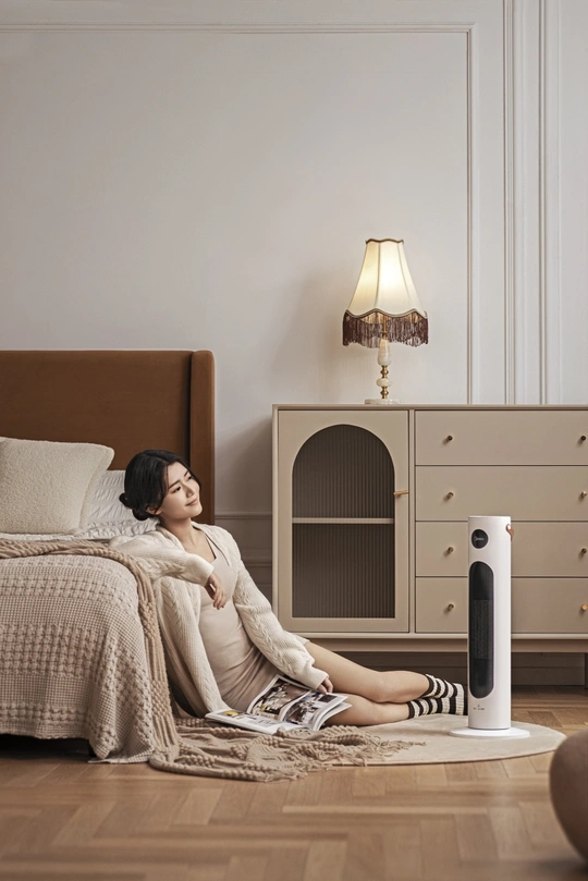 一位孕妇坐在卧室地板上 旁边是床和扬声器。