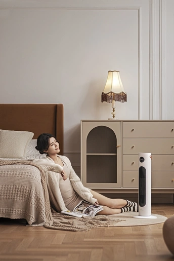 一位孕妇坐在卧室地板上 旁边是床和扬声器。