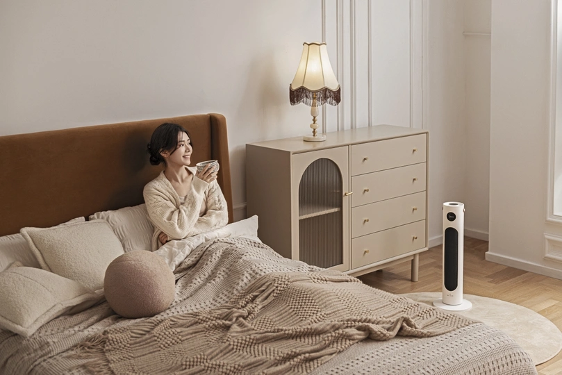 一个年轻女子坐在卧室的床上喝一杯茶