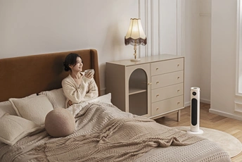 一个年轻女子坐在卧室的床上喝一杯茶