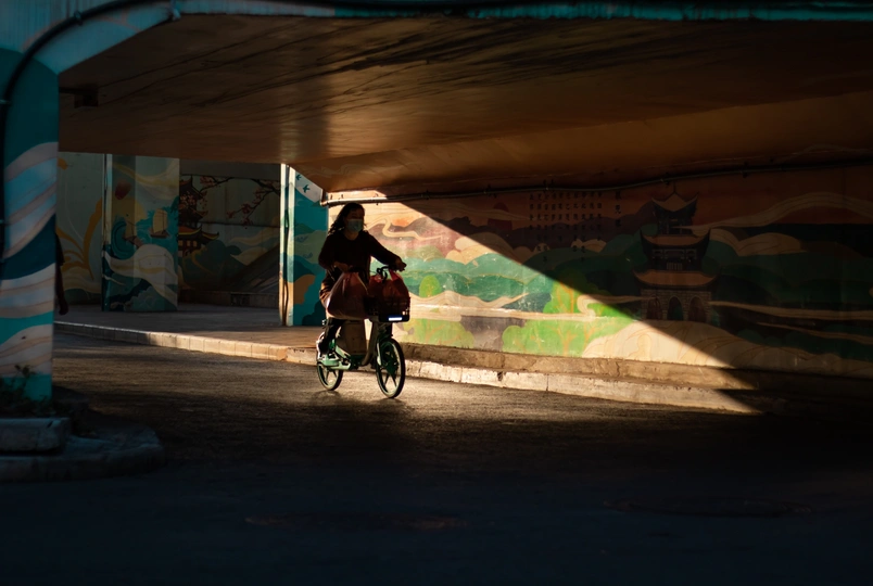 一个人骑自行车在街道下方的桥上