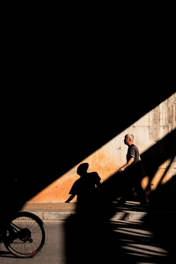一个人骑自行车在桥下街道上 墙上阴影斑驳