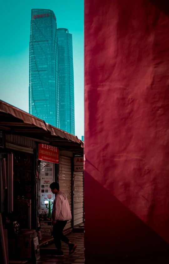 一个人走在一栋高楼旁边的一条街上