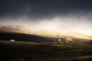 阳光透过云层照耀在一座山丘上的农场。