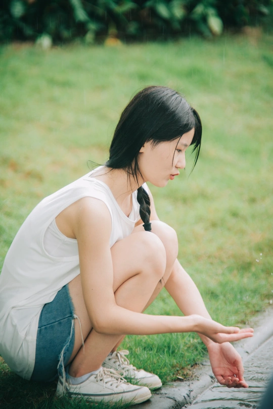 一位年轻女子双手高举坐在草地上