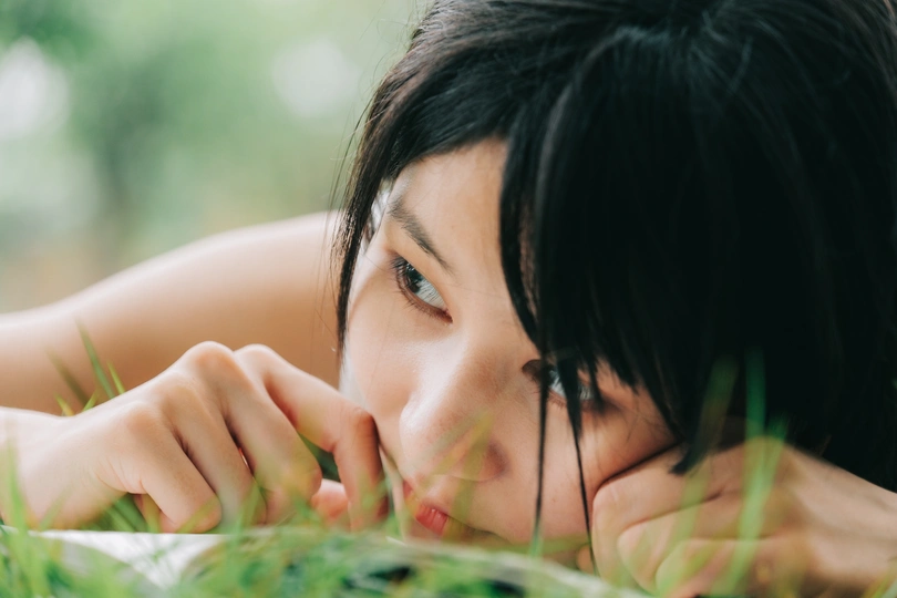 一个躺在绿草里看书的年轻女子