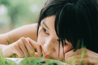 一个躺在绿草里看书的年轻女子