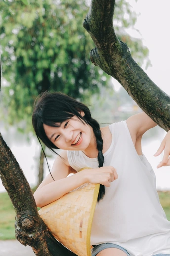 一位年轻女子坐在公园树下的秋千上