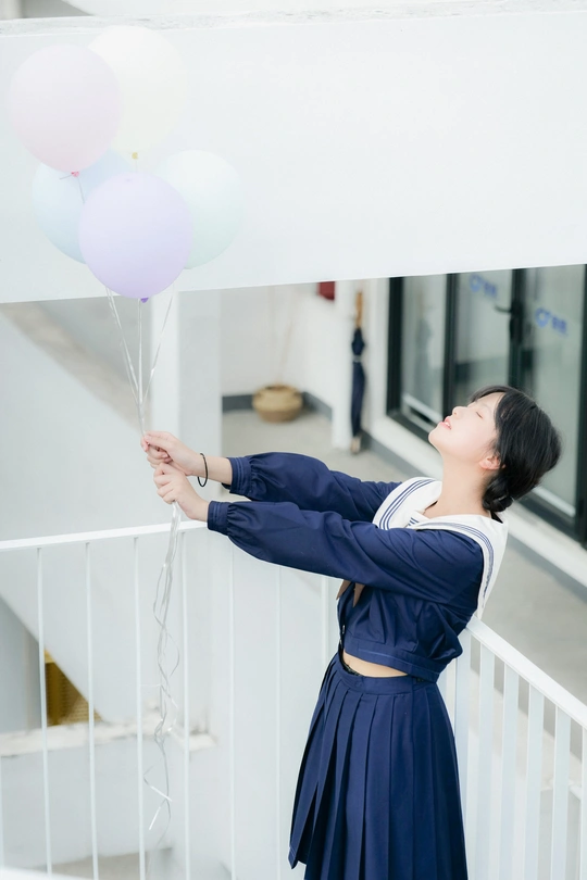 一个穿着蓝色连衣裙的年轻女子手里拿着白色气球