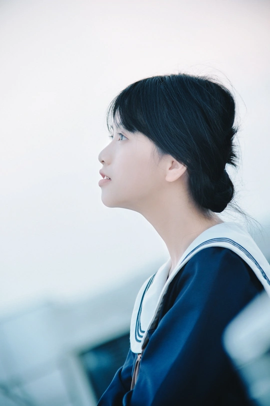 一个穿着蓝色衣服的年轻女子望着窗外