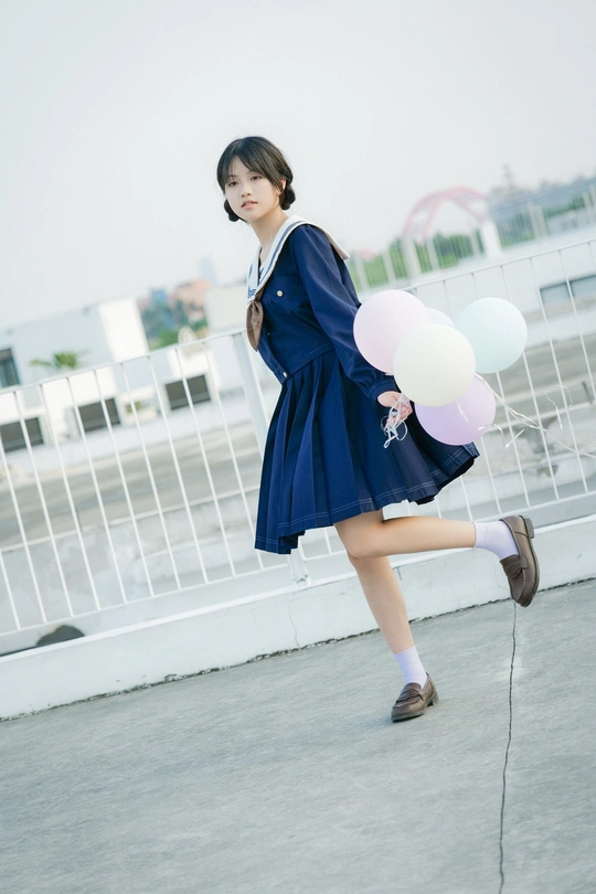 一个穿着蓝色连衣裙的年轻女子拿着气球走在街上
