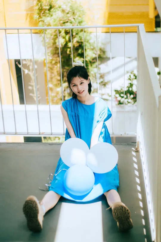 一个小女孩穿着蓝色裙子坐在楼梯栏杆上