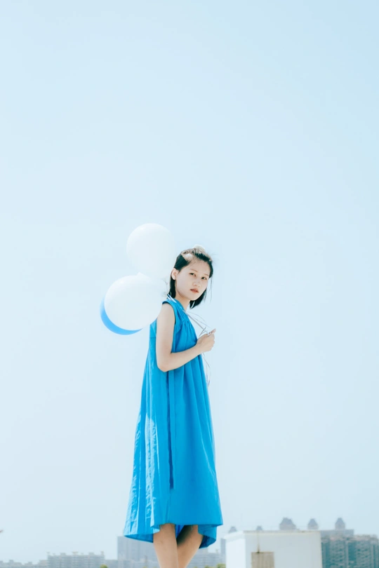 一个小女孩穿着蓝色裙子 手里拿着一个白色飞盘。