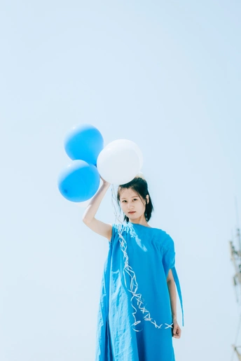 一个小女孩穿着蓝色裙子 拿着白色气球。