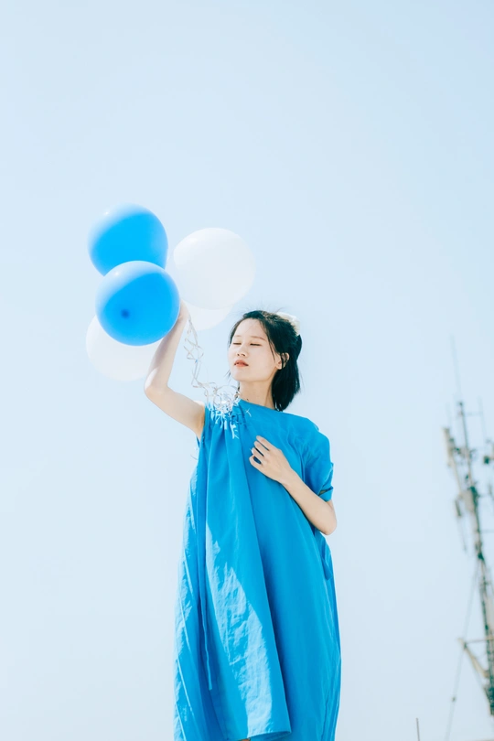 一位穿着蓝色连衣裙的年轻女子拿着气球