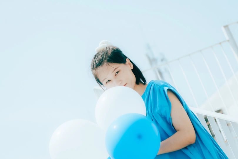 蓝色连衣裙的年轻女子拿着白色气球